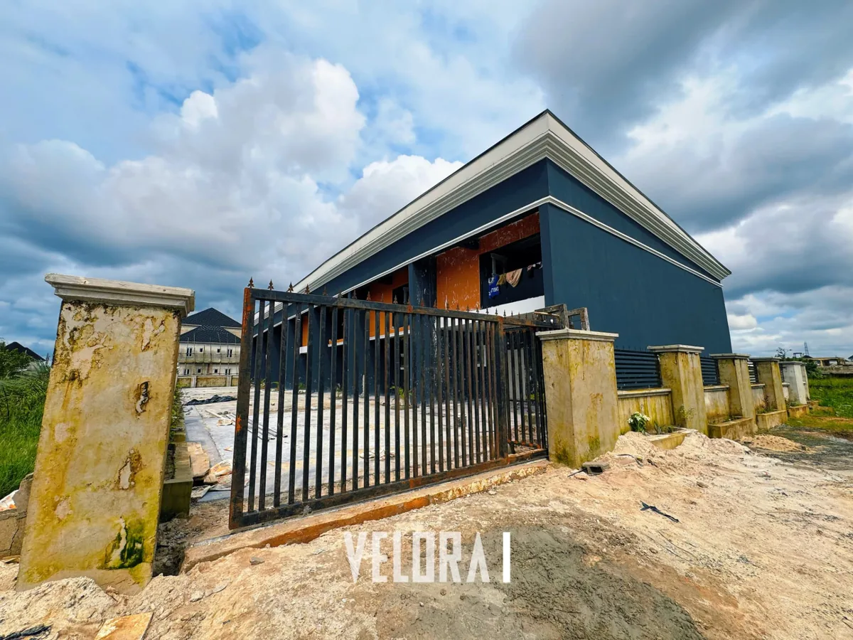 Velora 1 at Newtown Estate on SARS Road: entrance with a metal gate, pitched-roof gatehouse and perimeter pillars.